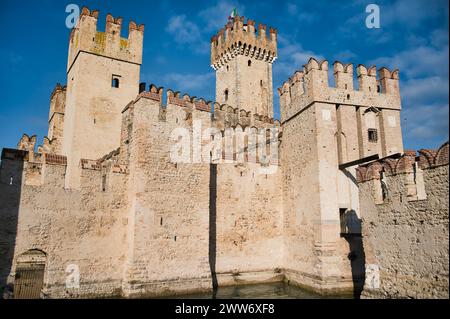 Wächter der Geschichte: Ein herrlicher Blick auf die antiken Steinmauern und die Türme der Burg Sirmione, die sich am Ufer des Gardasees thront Stockfoto