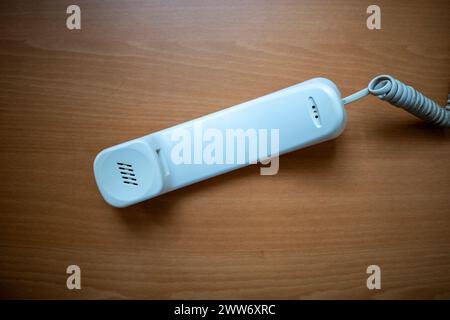Weißes Handset des Festnetztelefons auf Holztisch. Hintergrund des Telekommunikationskonzepts. Stockfoto