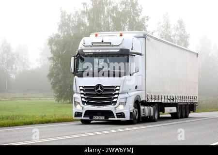 Der weiße Mercedes-Benz Actros 1848-Lkw-Auflieger transportiert an einem nebeligen Sommermorgen Güter auf der Autobahn. Salo, Finnland. August 2023. Stockfoto