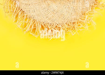 Minimalistische Urlaubsplanung einfaches Thema des Strohhutes auf einheitlichem gelbem Hintergrund, flach gelegt mit Kopierraum Stockfoto