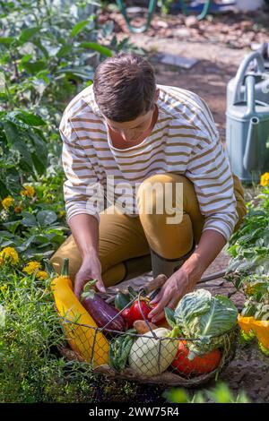 Eine junge Frau hockt vor ihrem mit Gemüse gefüllten Korb. Stockfoto