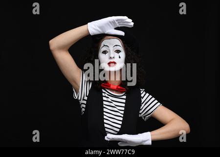 Eine junge Frau im Mime-Kostüm posiert auf schwarzem Hintergrund Stockfoto