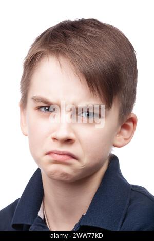 Ein kleiner Junge mit blauem Poloshirt, das die Stirn runzelt, als Ausdruck von Unmut oder Meinungsverschiedenheit. Studio-Porträt vor weißem Hintergrund Stockfoto