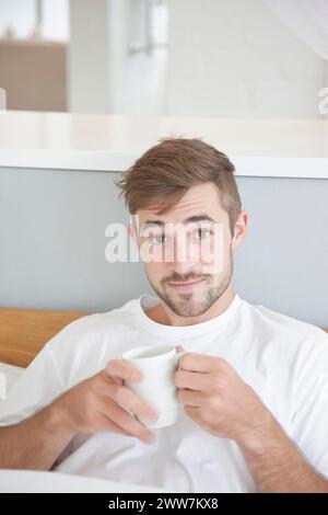 Mann, sitzend im Bett halten Mug Stockfoto