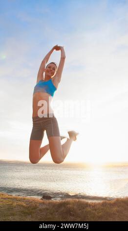 Frau springt mitten in der Luft am Strand, Low Angle view Stockfoto