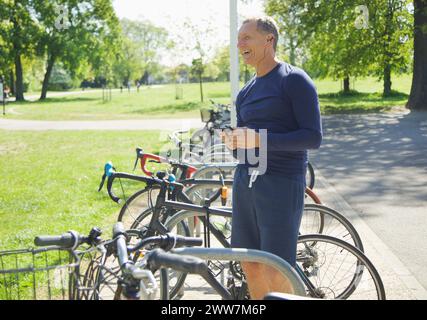 Reifer Mann im Park Musikhören auf Smartphone Stockfoto