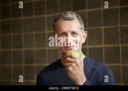 Reifer Mann hält einen Apfel Stockfoto