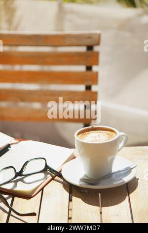 Cappuccino, Brillen und Notizblock auf Tisch im freien Stockfoto