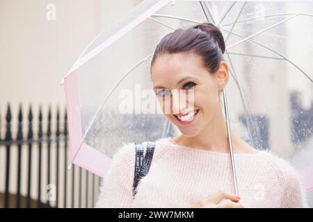Lächelnde Frau mit Regenschirm in einer Londoner Straße Stockfoto