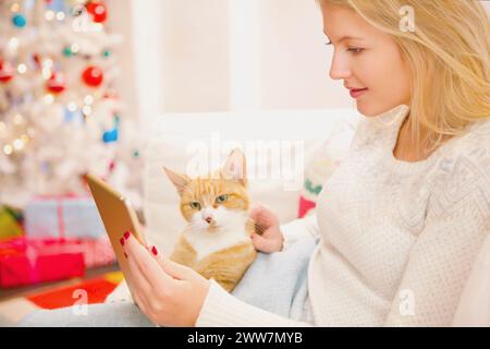Frau streicheln Katze während Using Digital Tablet Stockfoto
