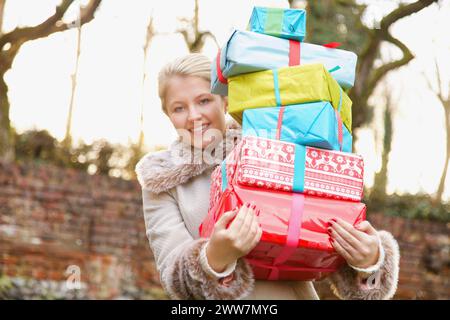 Junge Frau mit Stapel von Weihnachten präsentiert im freien Stockfoto