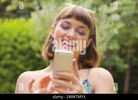 Lächelndes Teenager-Mädchen, Das Draußen Ein Smartphone Benutzt Stockfoto