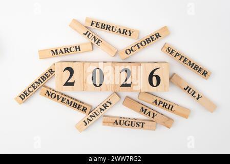 Holzklötze und -Würfel mit dem Jahr 2026 und den 12 Monaten des Jahres zufällig verstreut. Isoliert auf weißem Hintergrund. Stockfoto
