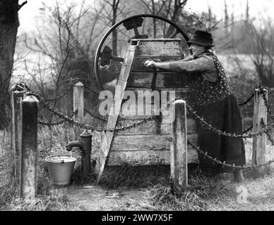 Frau pumpt Wasser aus einer öffentlichen Wasserpumpe in Kent, England, Großbritannien 1932 Stockfoto