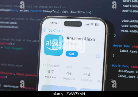 New York, USA - 23. Februar 2024: Amazon Alexa auf dem iphone-Bildschirm mit unscharfem Code-Programmierhintergrund Stockfoto