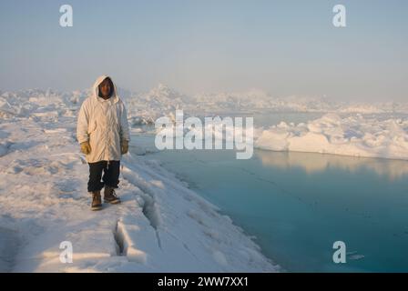 Ein Inupiaq-Existenzjäger steht auf rauem Packeis, nachdem er unweit der Küste, der Chukchi-See Alaska, instabile Meereisbedingungen beobachtet hat Stockfoto