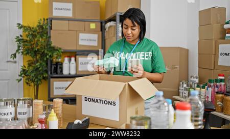 Hispanische Frau scannt Barcode im Spendenlager Stockfoto