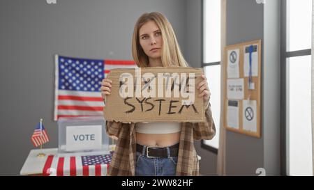 Eine junge Frau, die in einem Wahlstudienzimmer in den usa ein Schild mit dem Titel "Fix the System" hält und Aktivismus darstellt Stockfoto