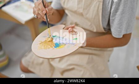 Nahaufnahme eines Mannes, der auf einer Palette in einem hell beleuchteten Atelier gemalt wird und Kreativität und Kunstfertigkeit zeigt. Stockfoto