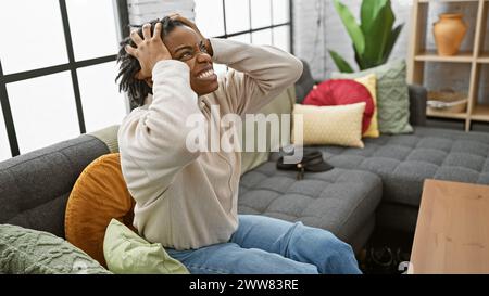 Junge gestresste afroamerikanerin mit Dreadlocks zu Hause auf dem Sofa Stockfoto