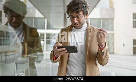 Ein stilvoller junger Mann interagiert mit seinem Smartphone auf einer Stadtstraße und spiegelt so das moderne urbane Leben wider. Stockfoto