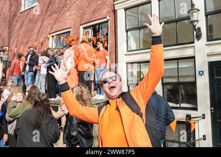 Lächelnde Menschen mit niederländischer Flagge im Gesicht und in orangefarbener Kleidung zum Königstag - Niederlande, Amsterdam, 27.04.2023 Stockfoto