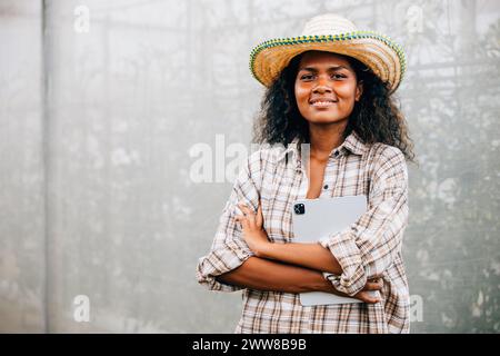 PhotoSuccessful Gewächshausbesitzer eine junge Frau in kariertem Hemd und Schürze steht mit überkreuzten Armen Stockfoto