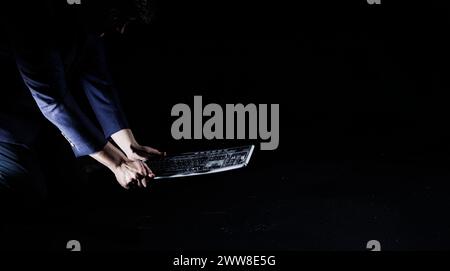 Geschäftsmann knallte hart eine Computertastatur auf einen Betonboden, zerstörte sie in kleine Stücke, Zeitlupenaufnahme. Überlastung und Burnout-Konzepte. Stockfoto