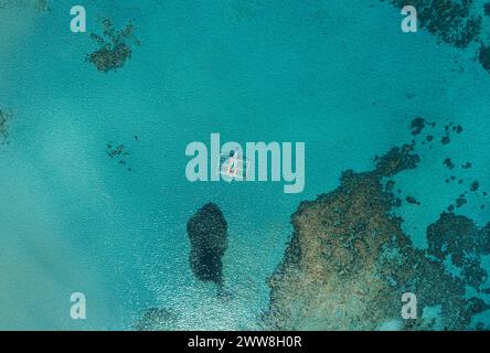 Blick von der Drohne auf das traditionelle philippinische Boot bangka, das an sonnigen Tagen in der Bucht mit klarem und türkisfarbenem Wasser vor Anker liegt. Boot in der tropischen Lagune Stockfoto