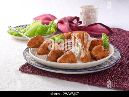 Hühnchen Tikka. Marinierte Hähnchenschenkelstücke auf Holzkohlen gegrillt und dann heiß mit Chilisauce, Gemüse usw. servieren Stockfoto