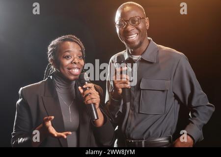 Taille hoch eines afroamerikanischen Paares auf der Bühne, das mit dem Mikrofon und dem Spotlight spricht Stockfoto