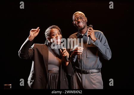 Die Taille ist hoch und das Entertainer-Duo auf der Bühne spricht zusammen mit dem Mikrofon Stockfoto