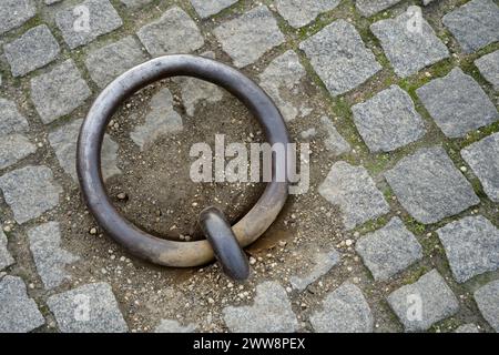 Rustikaler, verwitterter Eisenverankerring, eingebettet in Kopfsteinpflaster. Stockfoto