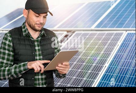 Fernsteuerung und Überwachung der Effizienz des Solarmoduls. Wartungsspezialist verwendet neben Solarpaneelen ein digitales Tablet. Stockfoto