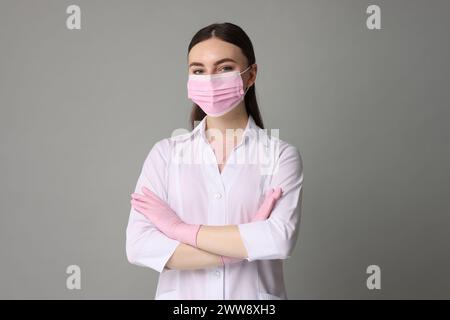 Kosmetologe in medizinischer Uniform auf grauem Hintergrund Stockfoto