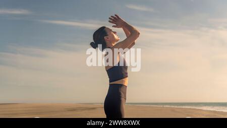 Frau, die am Strand steht und bei Sonnenaufgang und Sonnenuntergang meditiert Stockfoto