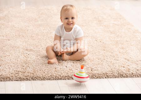 Kinderspielzeug. Süßer kleiner Junge und drehbares Top auf Teppich zu Hause Stockfoto