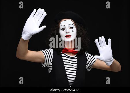 Eine junge Frau im Mime-Kostüm posiert auf schwarzem Hintergrund Stockfoto