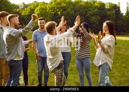 Fröhliche, fröhliche, junge multiethnische Freunde, die laut lachen und einander hohe fünf geben. Stockfoto