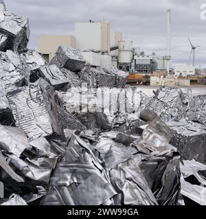 Gepresstes Schrott auf einer Schrottanlage im Hafen von Magdeburg in Deutschland, einer Fabrik im Hintergrund Stockfoto