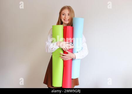 Eine Designerin oder Künstlerin hält Papierrollen in verschiedenen Farben in den Händen, grün, rosa, blau Stockfoto