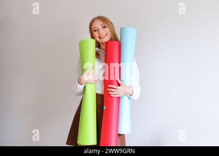 Eine Designerin oder Künstlerin hält Papierrollen in verschiedenen Farben in den Händen, grün, rosa, blau Stockfoto