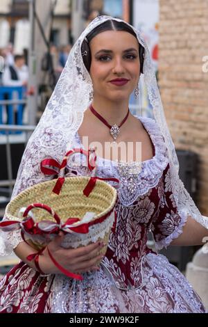 Burgundische Eleganz im Fallas; Eine Frau in einem traditionellen Fallera-Kostüm, verziert mit Spitze und Bändern, hält den Geist von Gandias Festival in sich Stockfoto