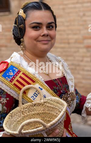 Valencianische Eleganz im Vollformat. Die Kleidung einer Fallera, reich an Rot und weiß mit goldenen Akzenten, fängt den Geist von Gandias Fallas-Festival ein. Stockfoto