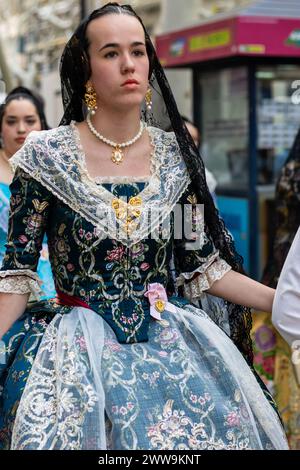 Grüne Eleganz im Gandia’s Fallas; das dunkelgrüne Kleid Einer Fallera, das mit Blumen bestickt ist, schließt eine rosa Blüte ein und symbolisiert das lebhafte Festival Stockfoto
