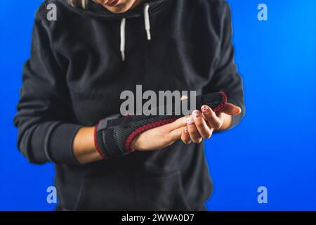 Frau zeigt eine zweiseitige Schiene auf ihrem Mittelfinger, verletzter Finger Konzept blauer Hintergrund. Hochwertige Fotos Stockfoto