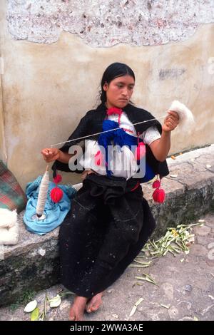 Am Montag, den 20. Dezember 1976, in San Juan Chamula, im zentralen Hochland von Chiapas im Süden Mexikos, verwendet eine Frau der Tzotzil Maya in traditioneller Kleidung eine klassische Wirbelspindel, um Wolle in Garn zu verwandeln. ein wichtiger Schritt bei der Herstellung der Kleidung, die sie auf ihrem traditionellen Rückenriemen Webstuhl webt. Stockfoto