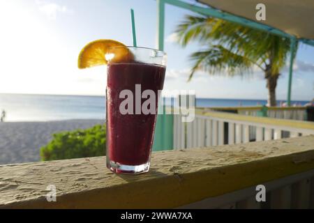 Tropisches gefrorenes Getränk mit Orangenscheibe und Meeresstrand-Szene im Hintergrund Stockfoto