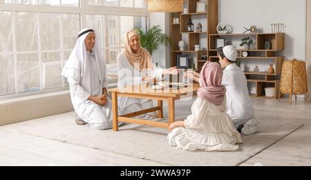 Glückliche muslimische Familie isst Süßigkeiten im Wohnzimmer Stockfoto
