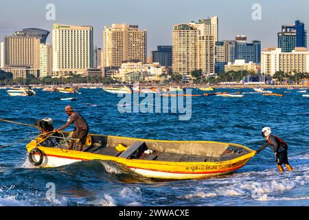 Fischer in einem kleinen Boot im Meer mit Pattaya Hochhäusern im Hintergrund, Thailand Stockfoto